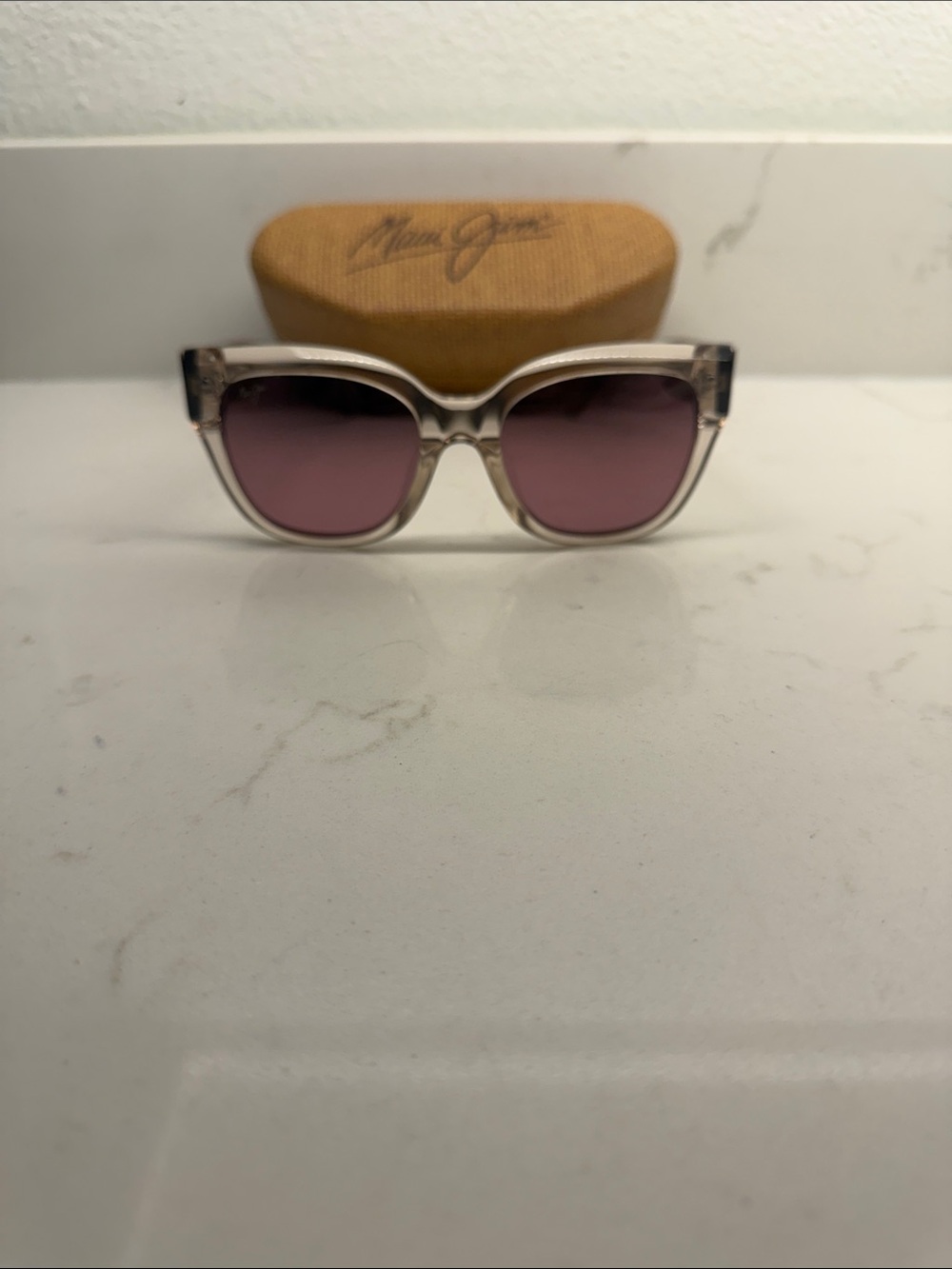Maui Jim iridescent clear frame sunglasses with light pink/mauve lenses.
